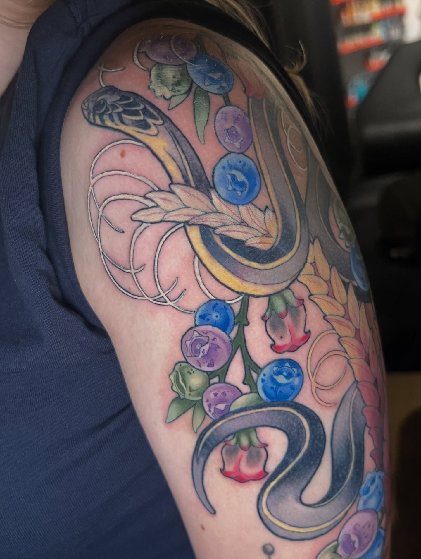Snake and berries new school tattoo on the upper arm by Belle Halverson