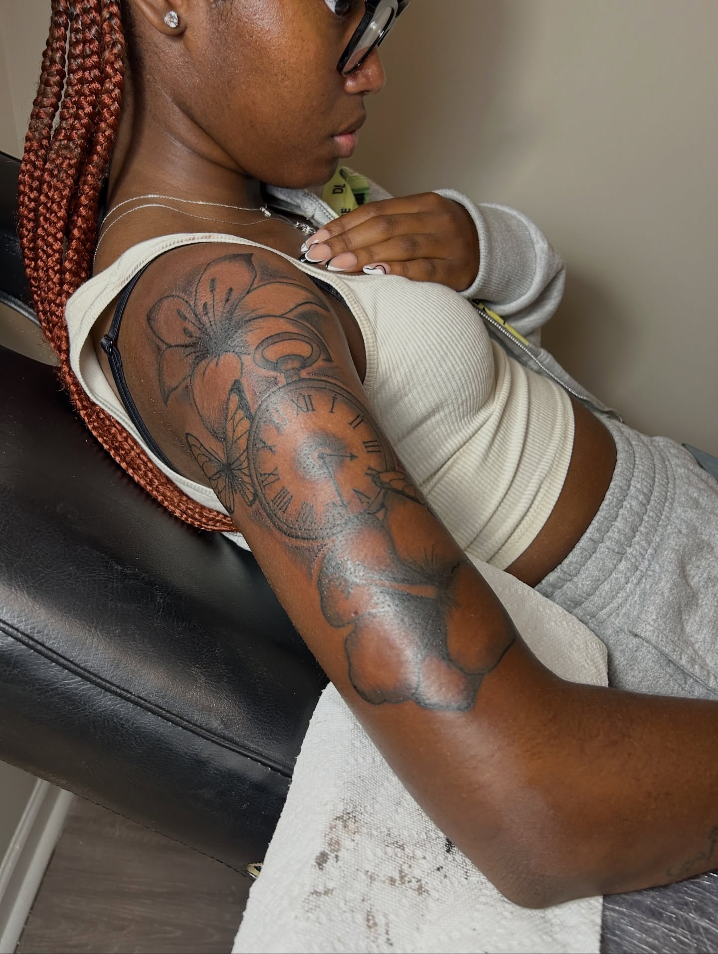 Clock and floral black and grey tattoo on the upper arm by nylachanel
