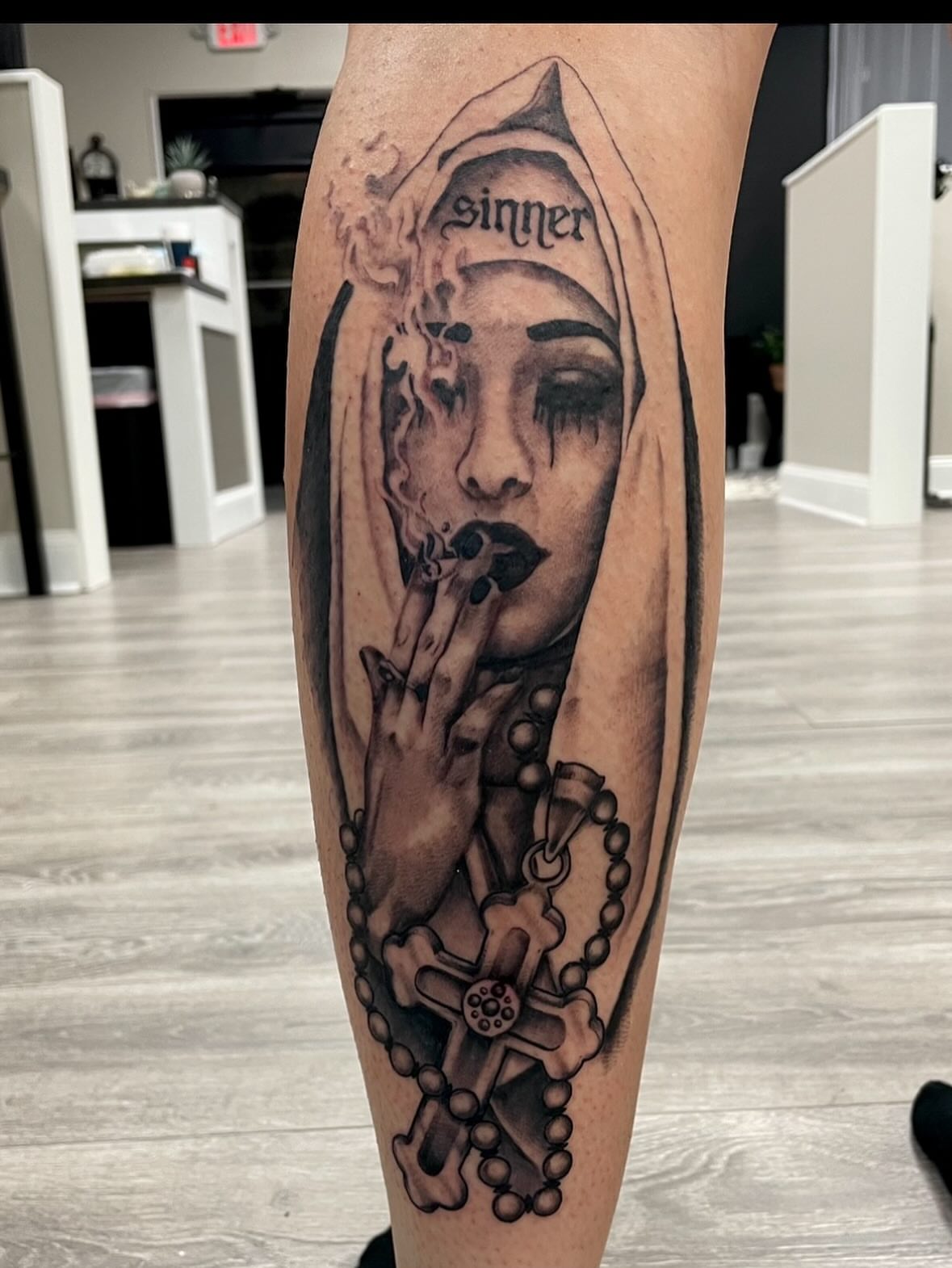 Woman with cross realism tattoo on the calf by Robbie Bryant