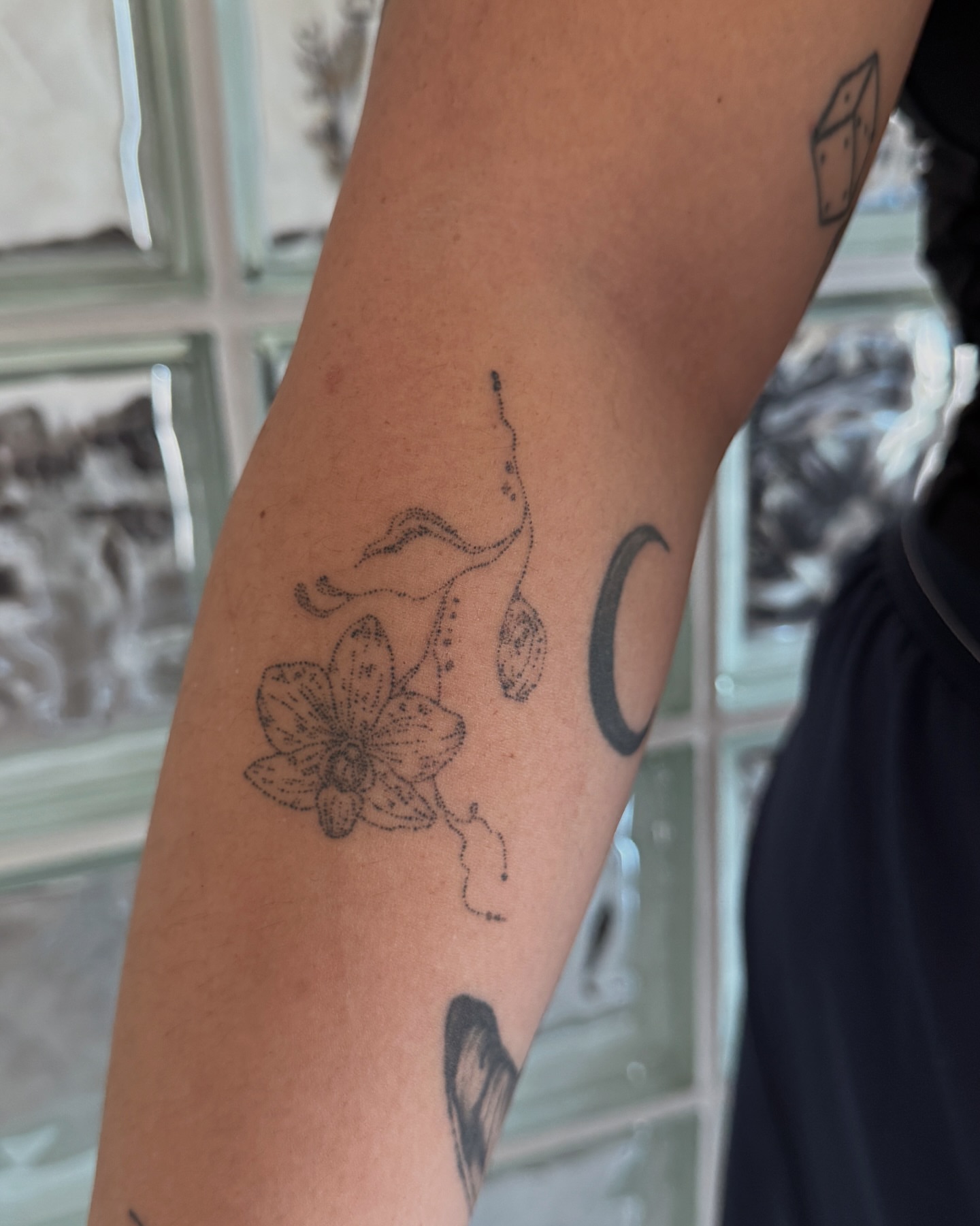 Orchid and abstract shapes dotwork tattoo on the forearm by Inky Apricot, Austin, Texas