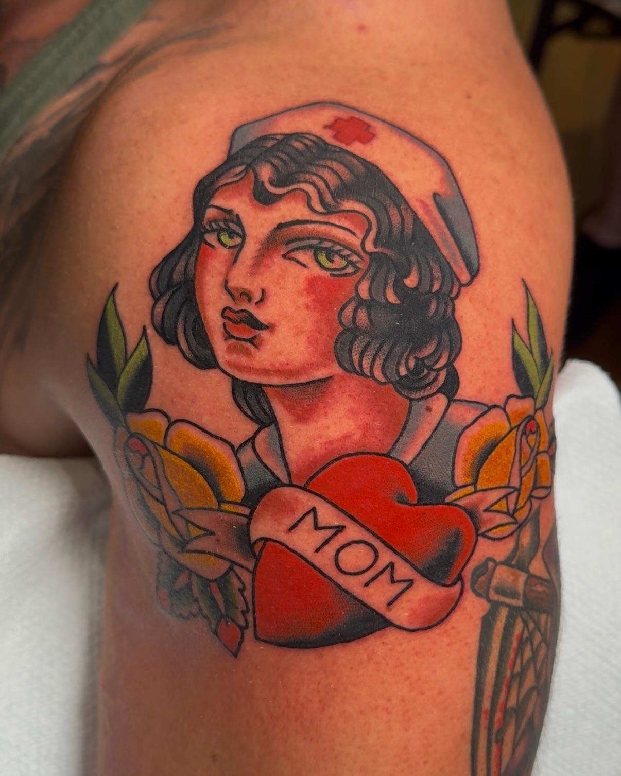 Nurse with roses American traditional tattoo on the upper arm by πππ’π―π’π¨ πππΆπ©π¬π―π, Manchester, New Hampshire