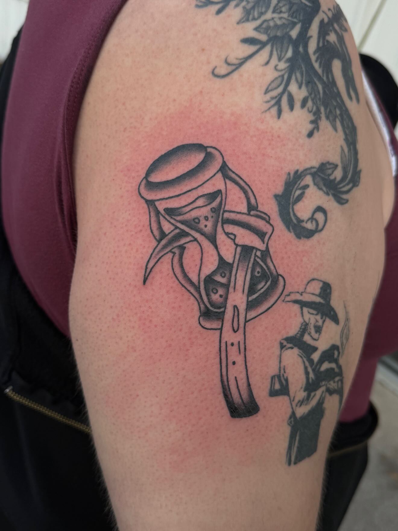 Hourglass and cowboy black and grey tattoo on the shoulder by frankie quadrini