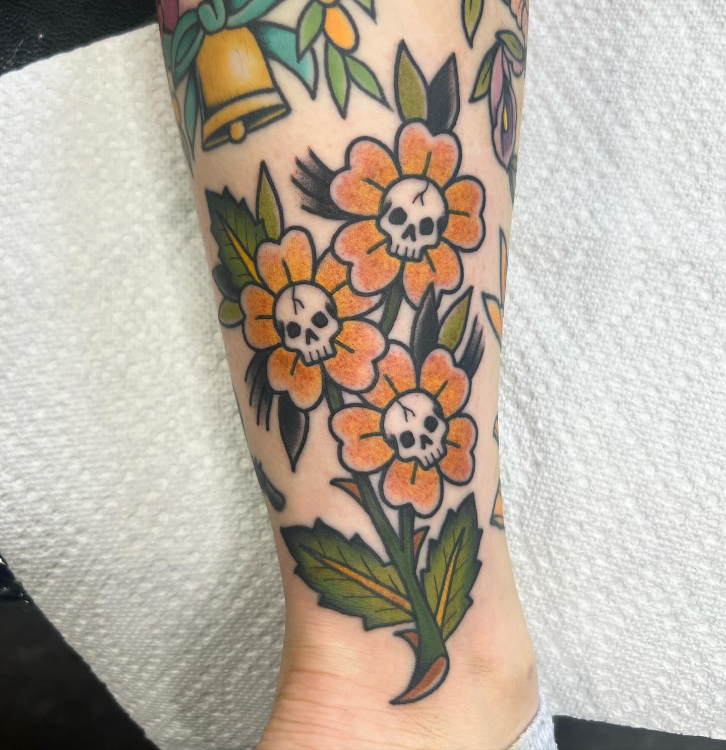 Skulls and flowers American traditional tattoo on the forearm by Taylor Estrella