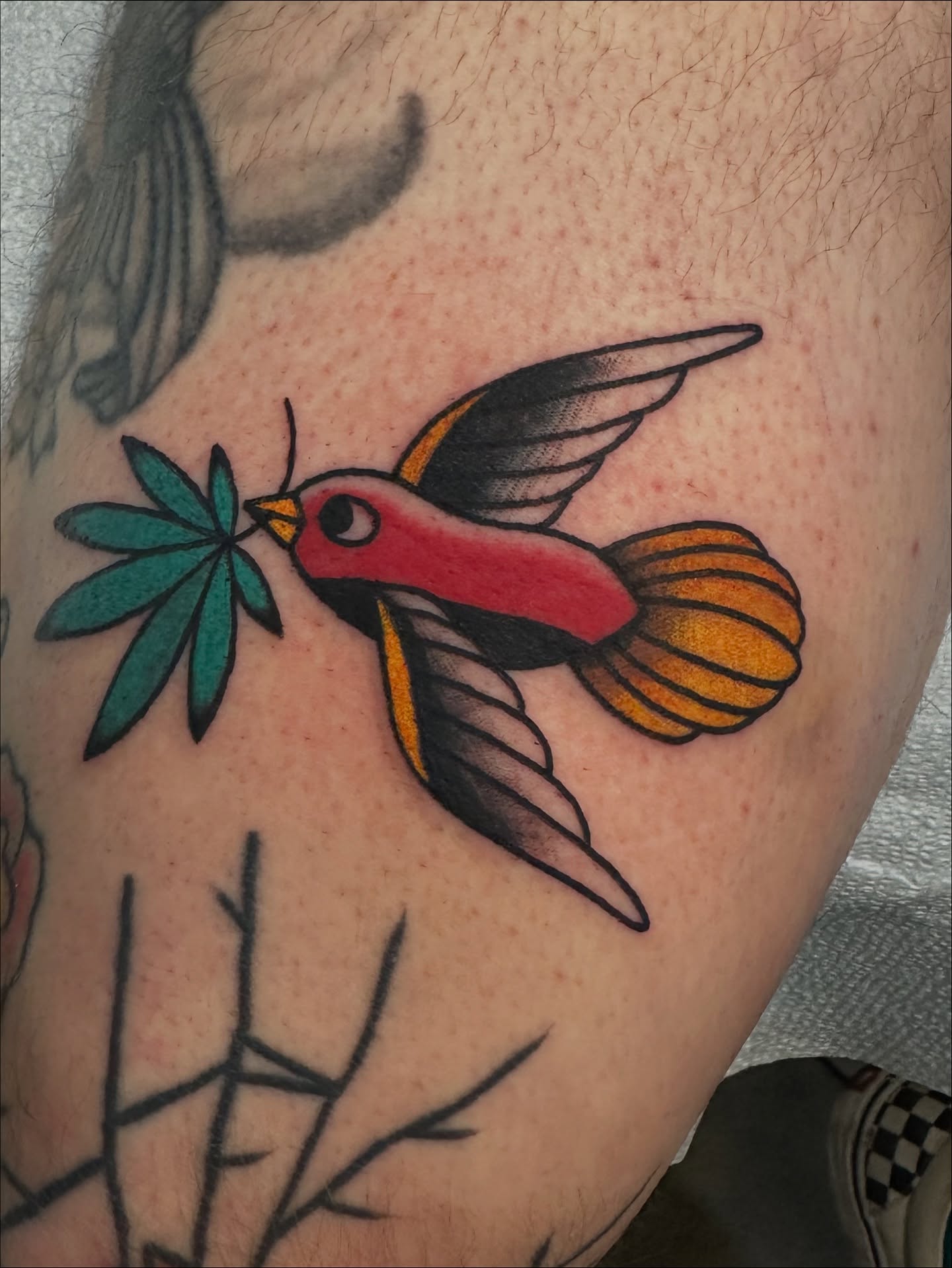 Bird and leaf American traditional tattoo on the upper arm by Emily Masa