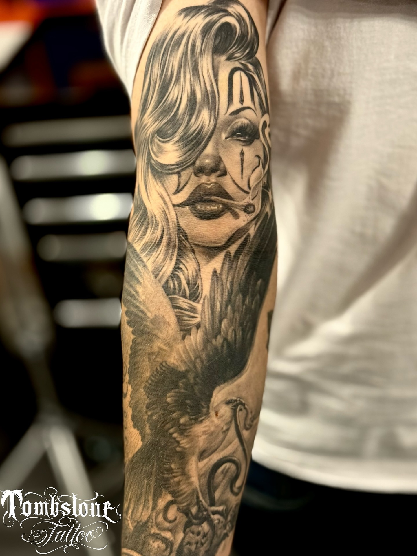 Woman with eagle realism tattoo on the forearm by tombstone