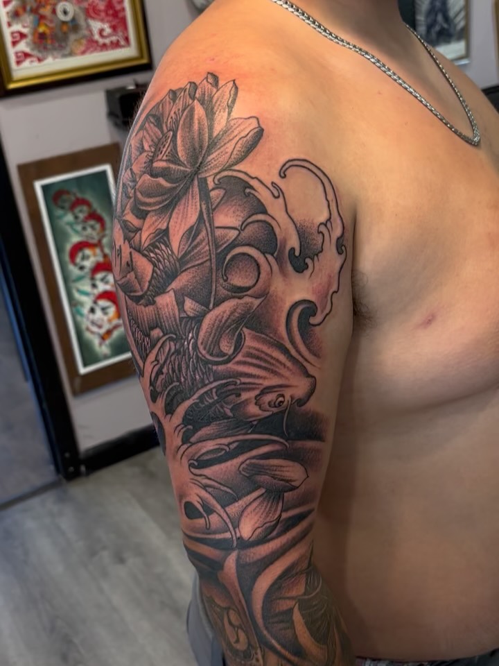 Lotus flower black and grey tattoo on the upper arm by michael