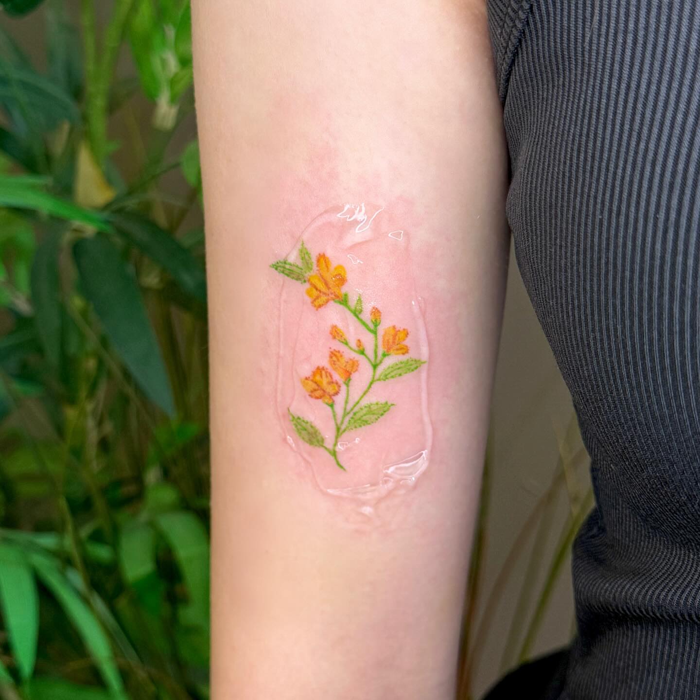 Orange flowers watercolor tattoo on the forearm by Yez tattoo