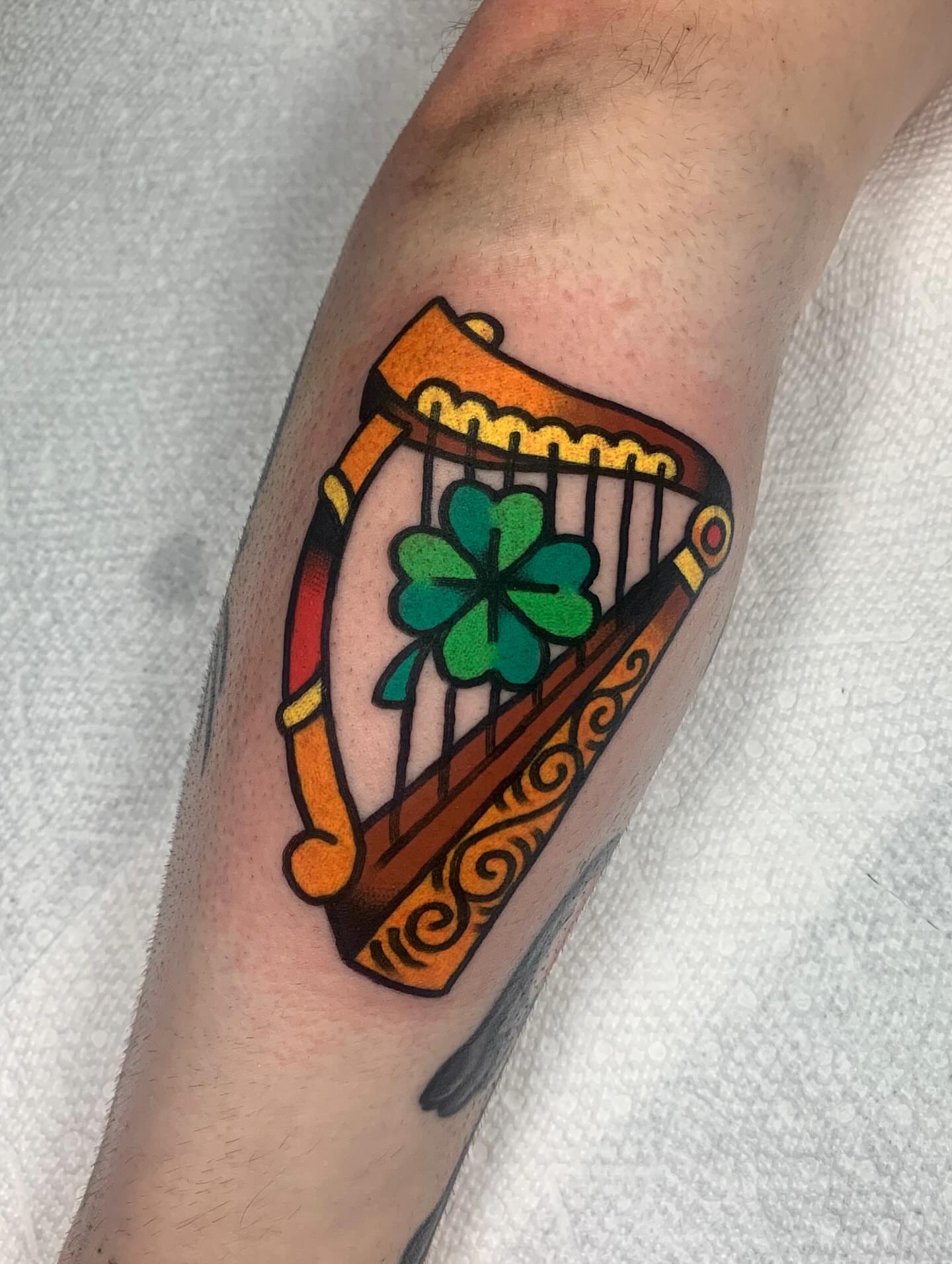 Irish harp and shamrock American traditional tattoo on the forearm by Shawn VanKirk