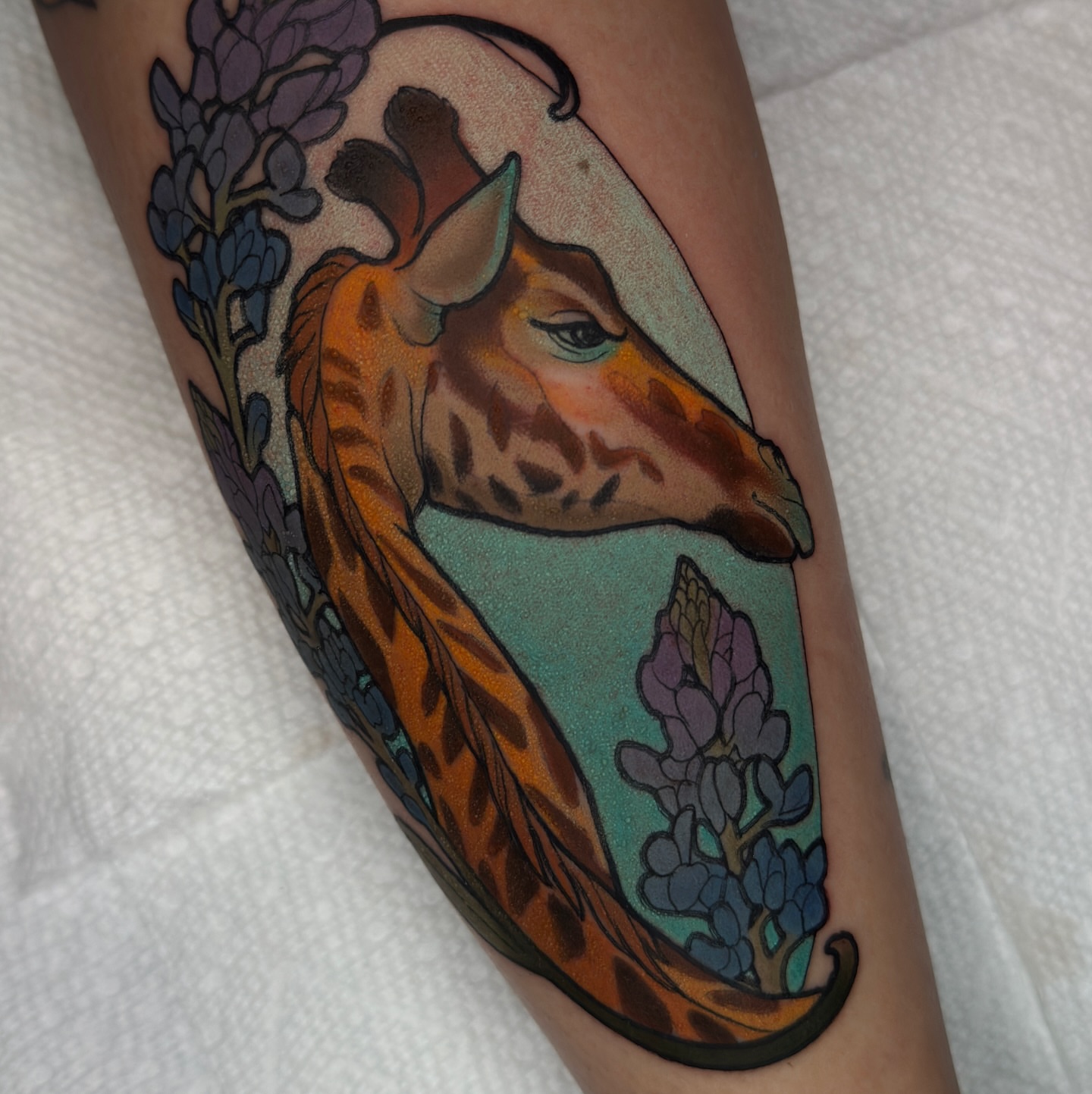 Giraffe and lupine realism tattoo on the forearm by Golden Heart Tattoo Co