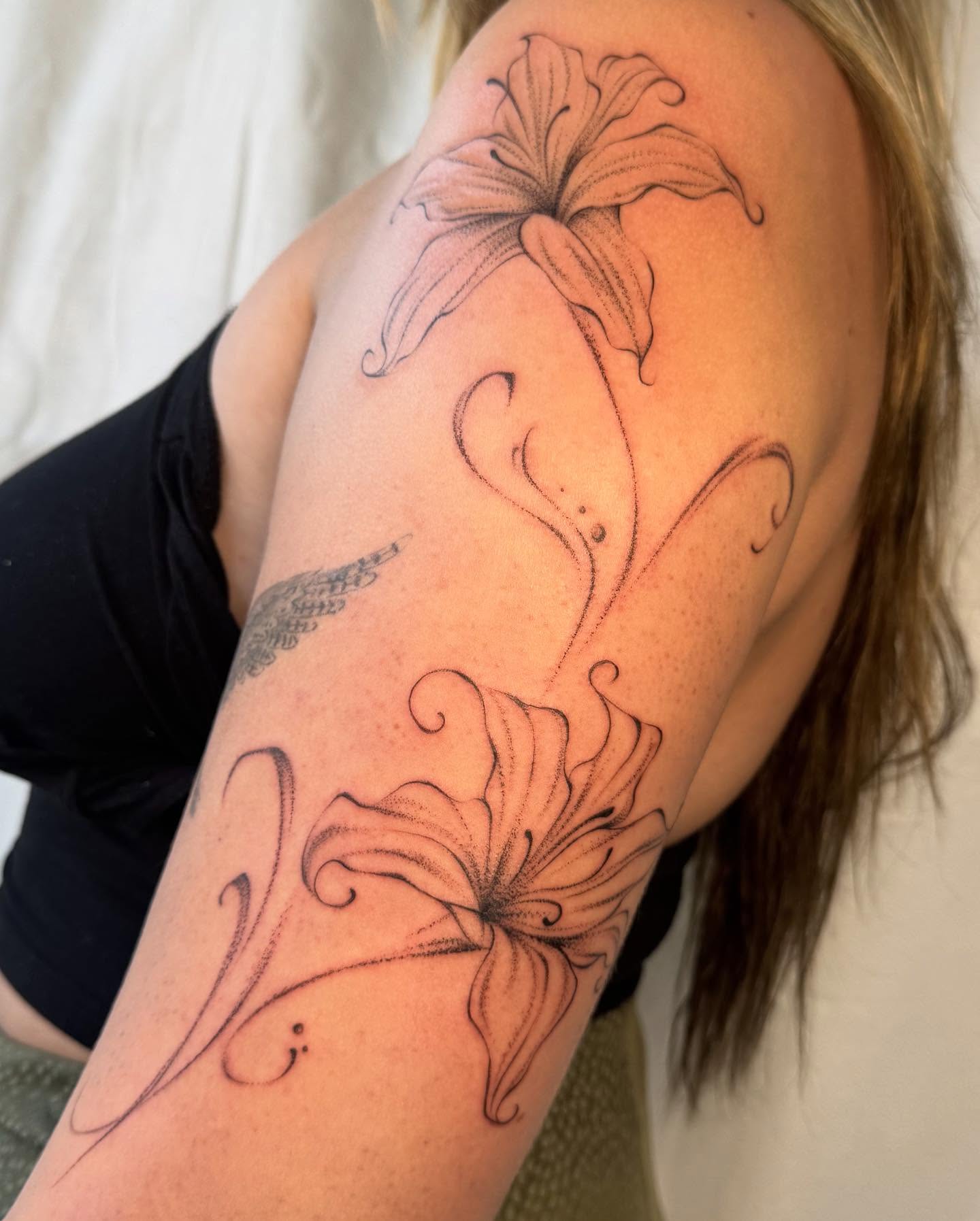 Lily black and grey tattoo on the upper arm by RyAnn Lynn