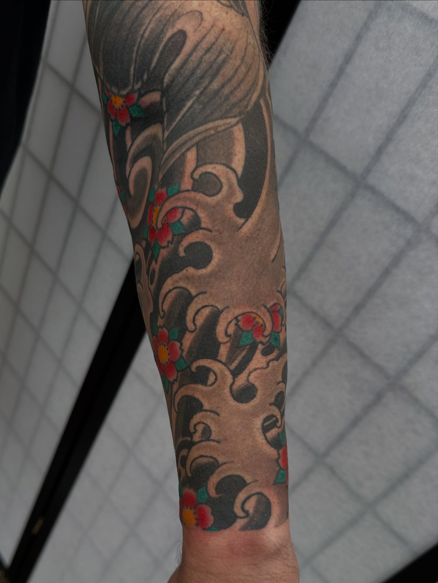 Wave and flowers japanese irezumi tattoo on the forearm by Daniel Skillingstead