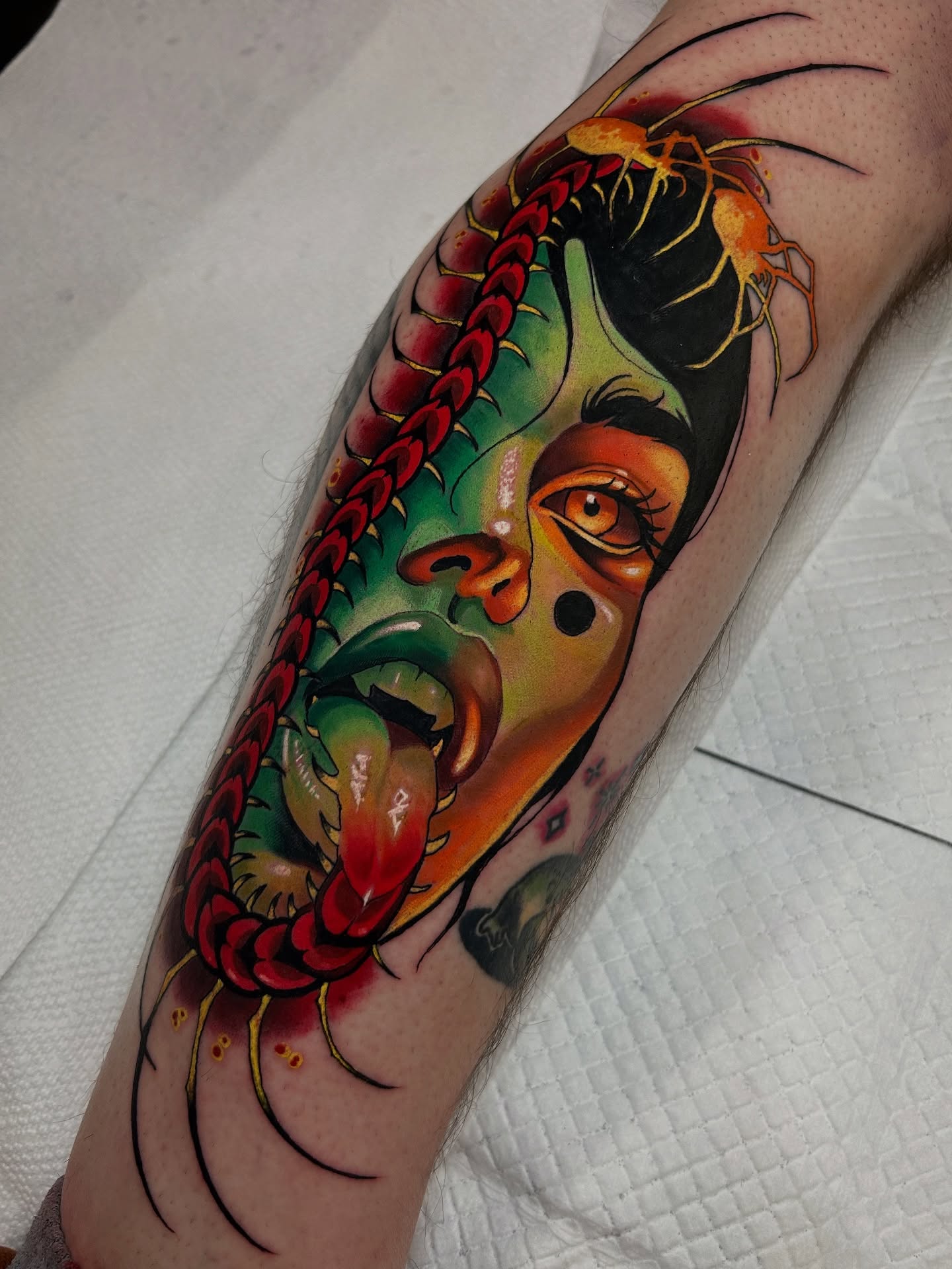 Mask with serpentine elements American traditional tattoo on the forearm by Matt Stolzenburg