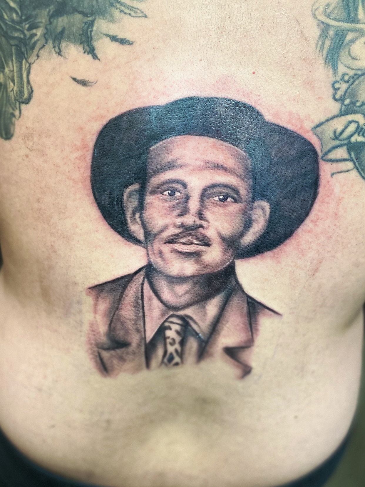 Man wearing hat realism tattoo on the chest by Rico Rosario