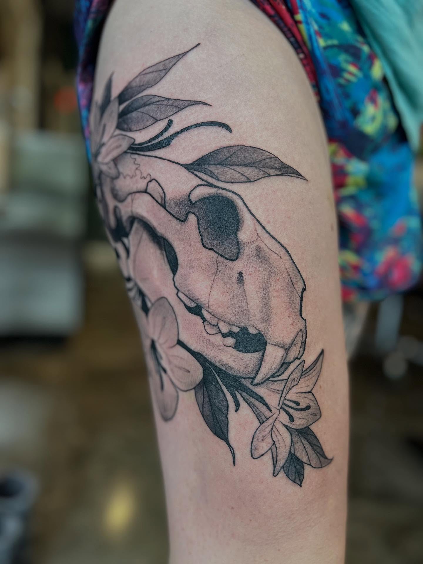 Skull and flowers realism tattoo on the thigh by Ian White