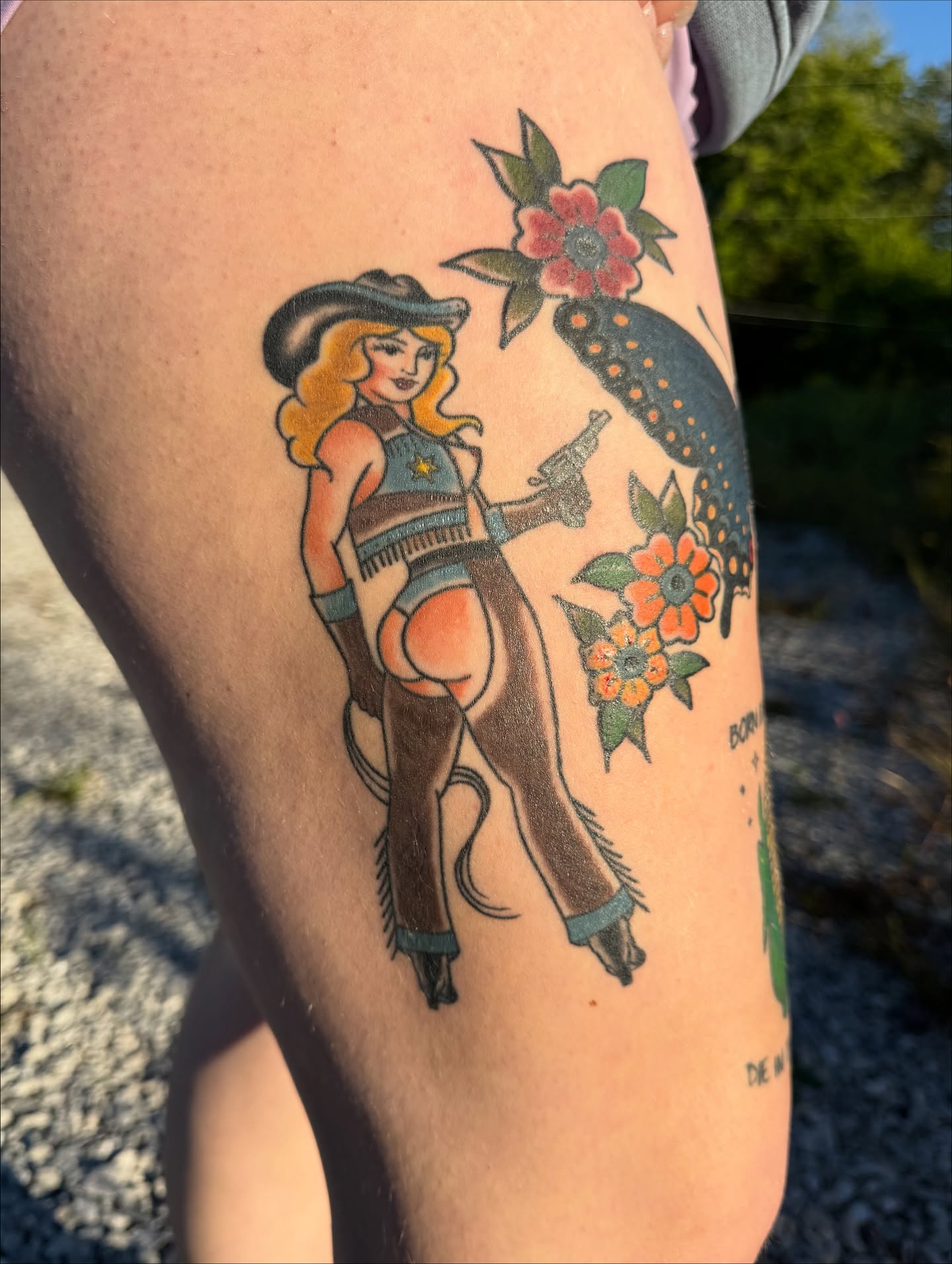 Cowgirl with butterfly American traditional tattoo on the thigh by Cora Phelps