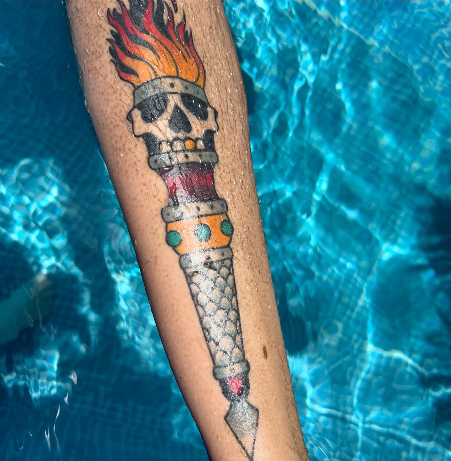 Flame-topped skull American traditional tattoo on the forearm by Courtney