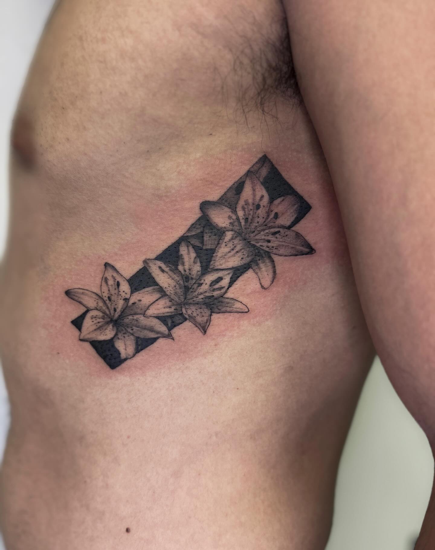 Lilies dotwork tattoo on the ribs by Rachel