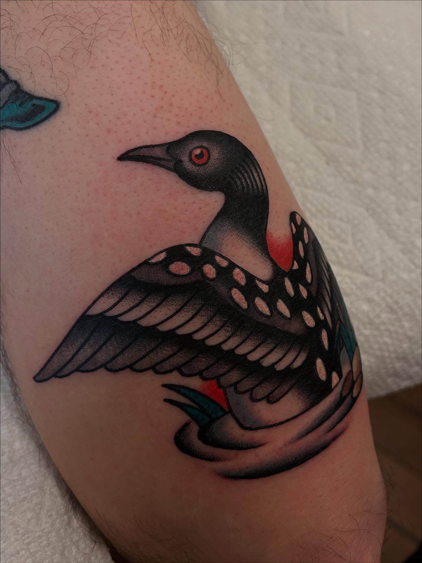 Loon American traditional tattoo on the upper arm by Christian Lasyone