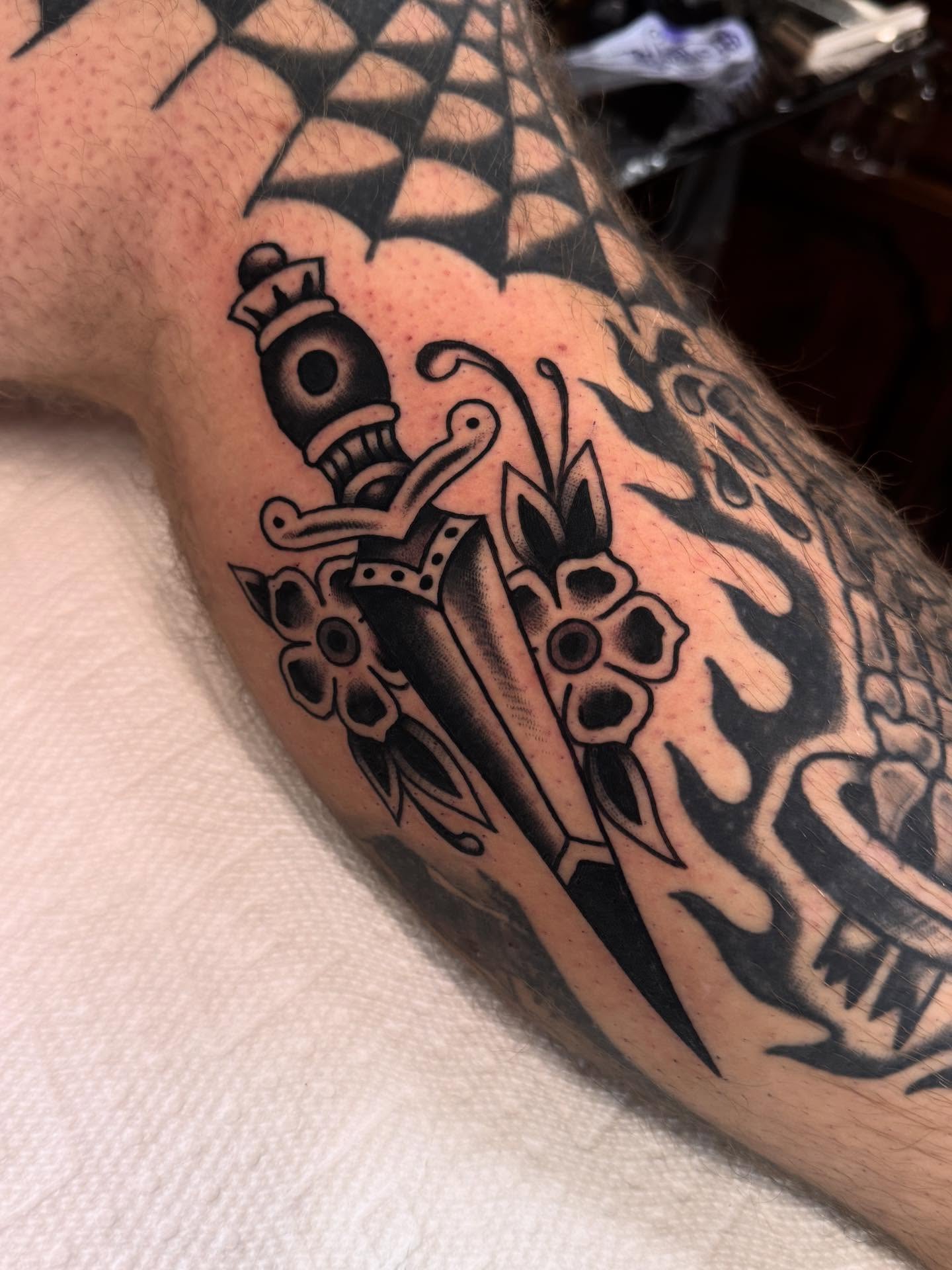 Sword and flowers black and grey tattoo on the forearm by Ryan Engels