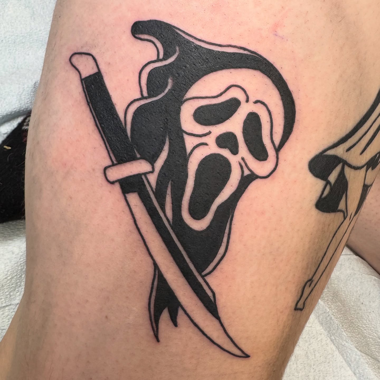 Ghost mask with knife black and grey tattoo on the thigh by Michael Roehrich (MEECH!)