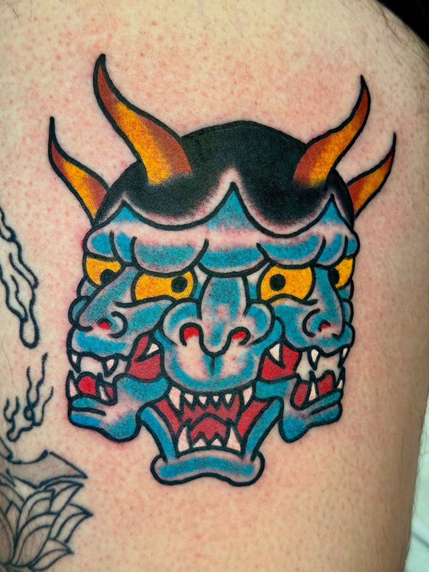 Demon mask American traditional tattoo on the shoulder by Joe Bear Tattooer