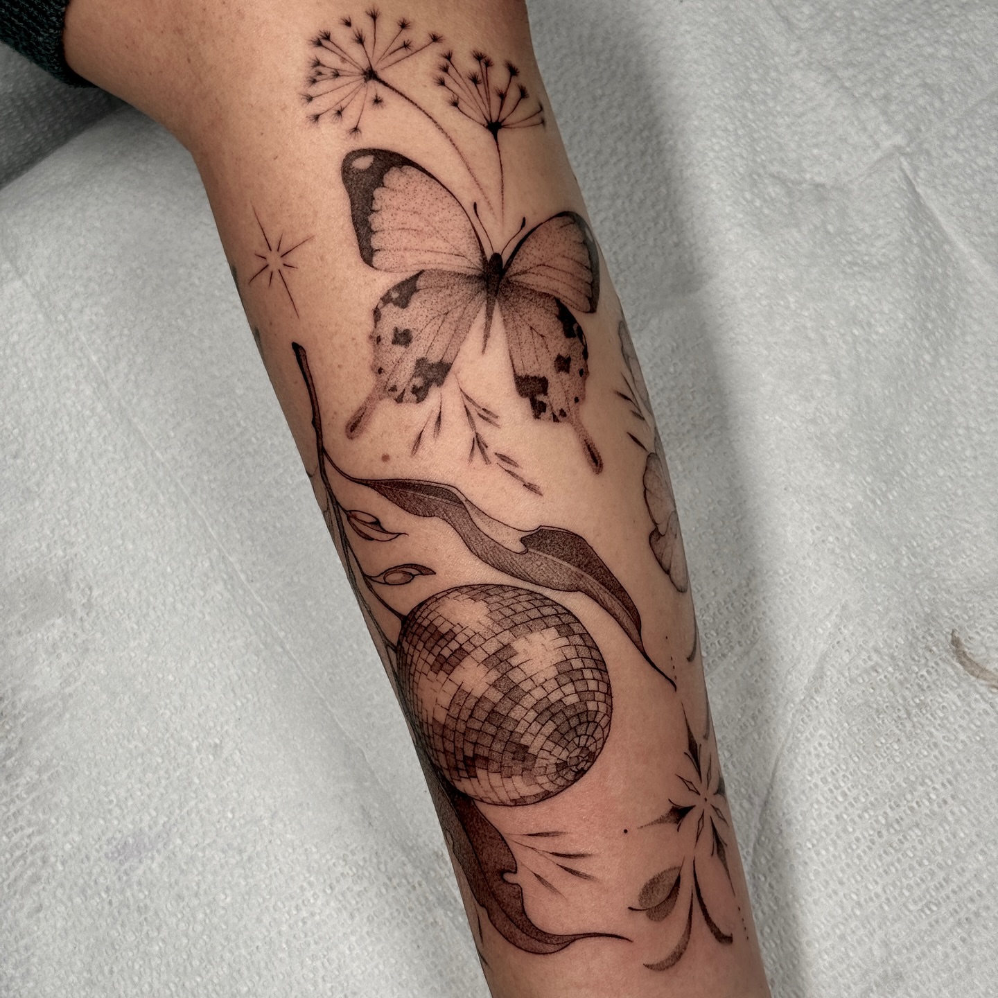Butterfly and disco ball realism tattoo on the forearm by Molly Murray