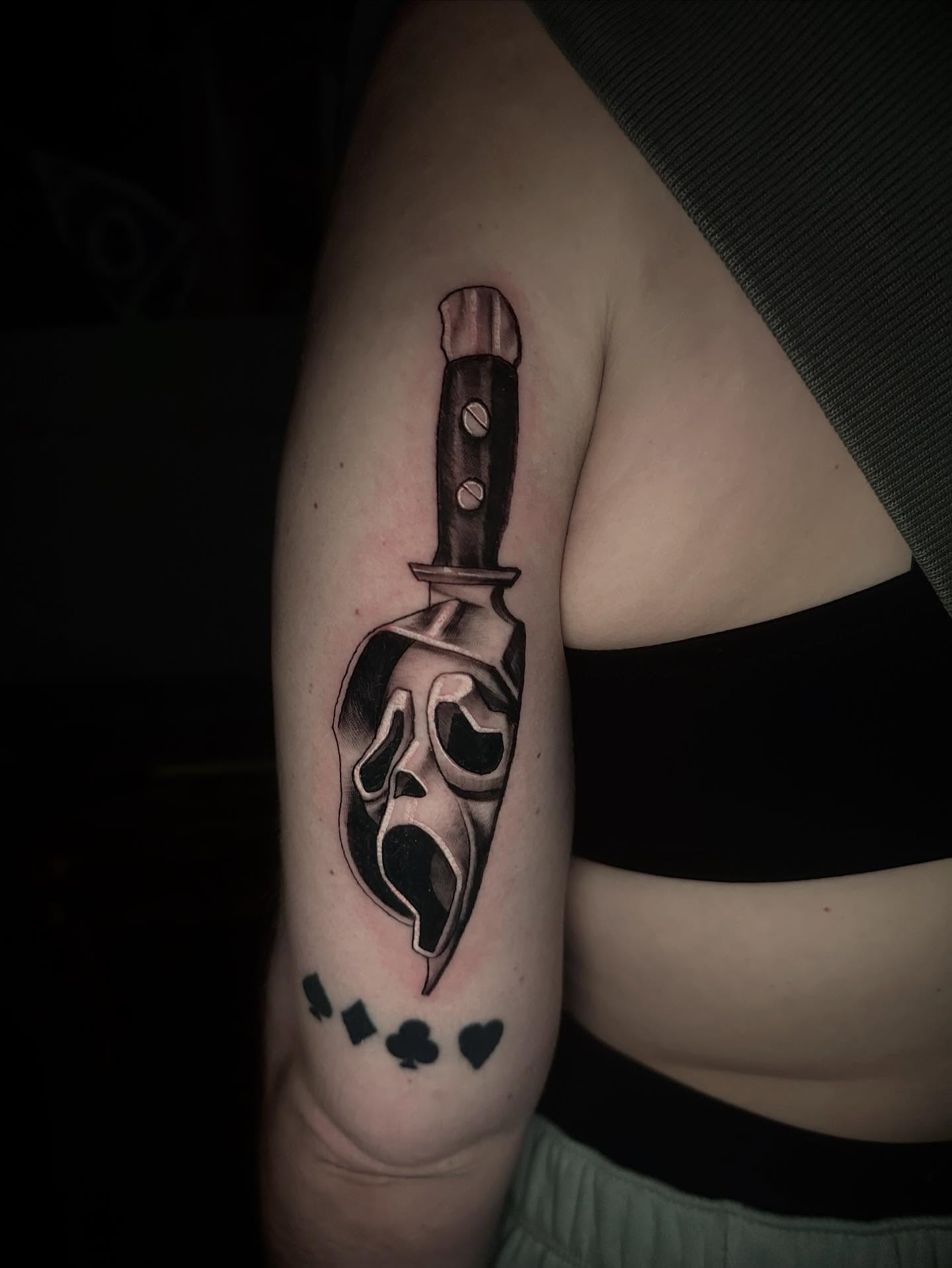 Knife with ghost face realism tattoo on the forearm by Javier Rivera