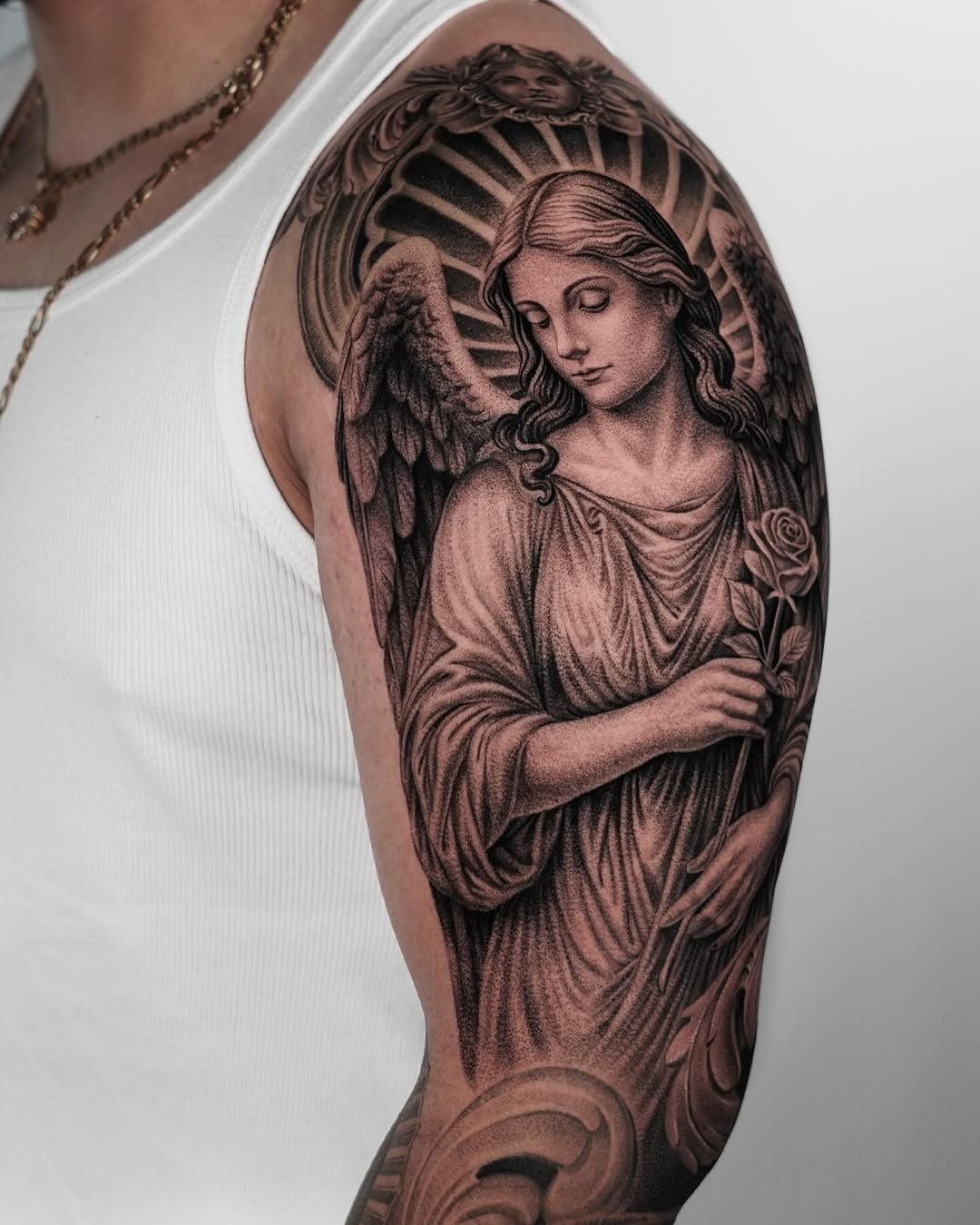Angel holding a rose realism tattoo on the upper arm by Enrique Martinez