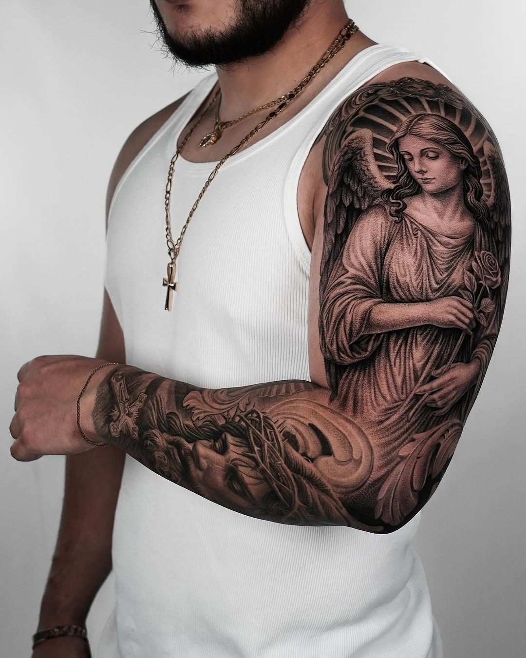 Angel with rose and religious imagery realism tattoo on the upper arm by Enrique Martinez