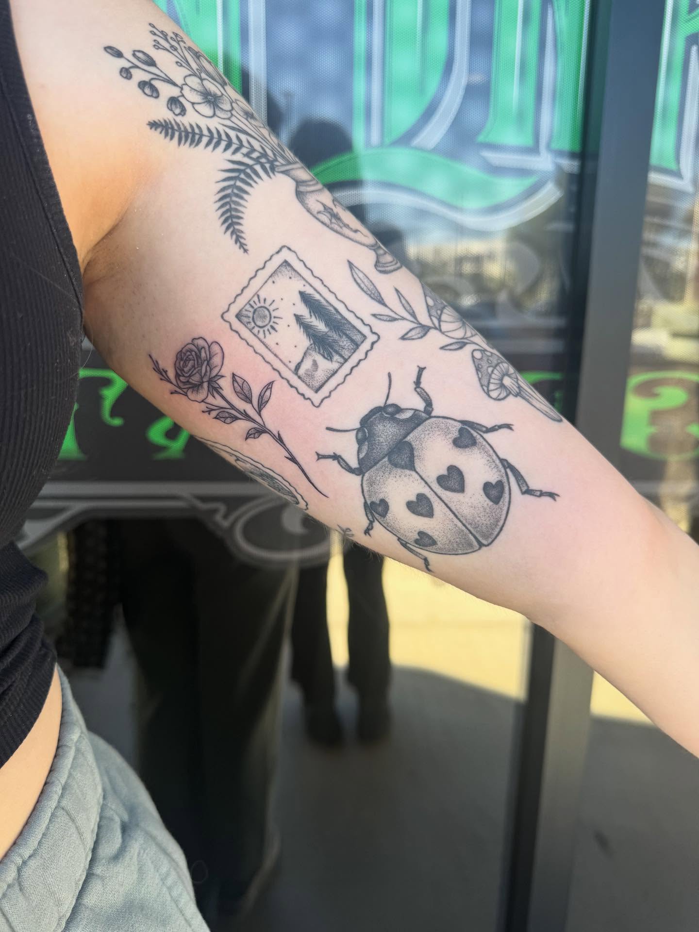 Ladybug black and grey tattoo on the forearm by Jianna
