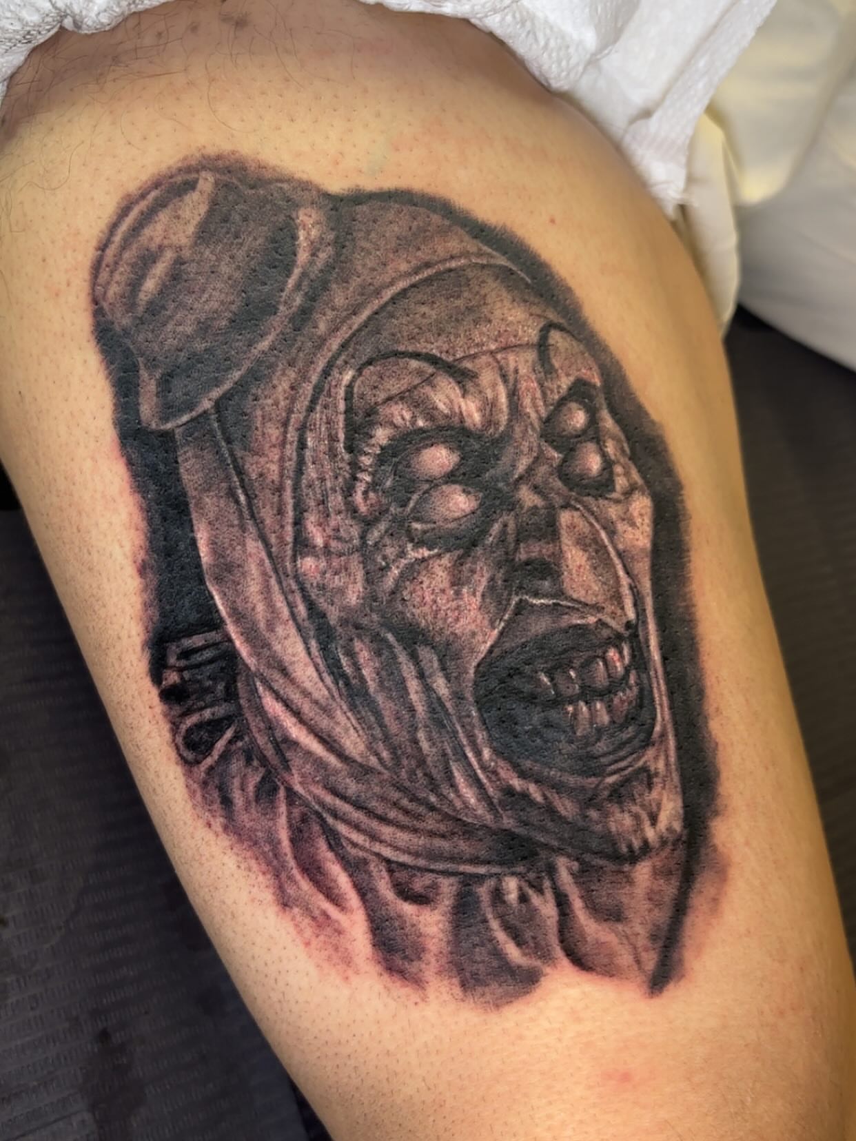 Mask black and grey tattoo on the thigh by Dre Ortiz