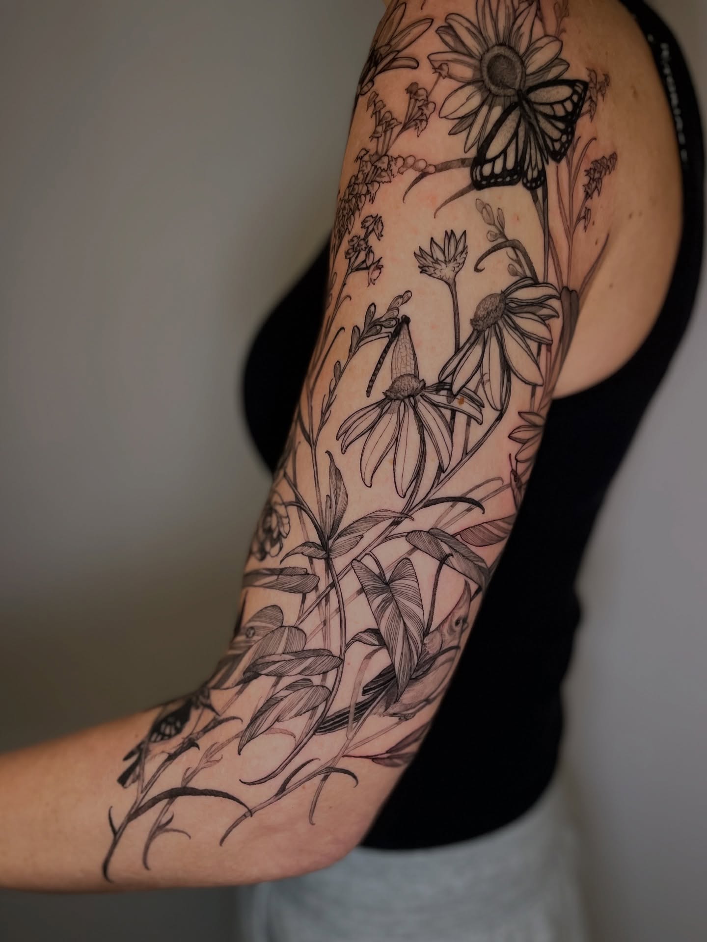 Floral arrangement black and grey tattoo on the upper arm by Carol Jacky