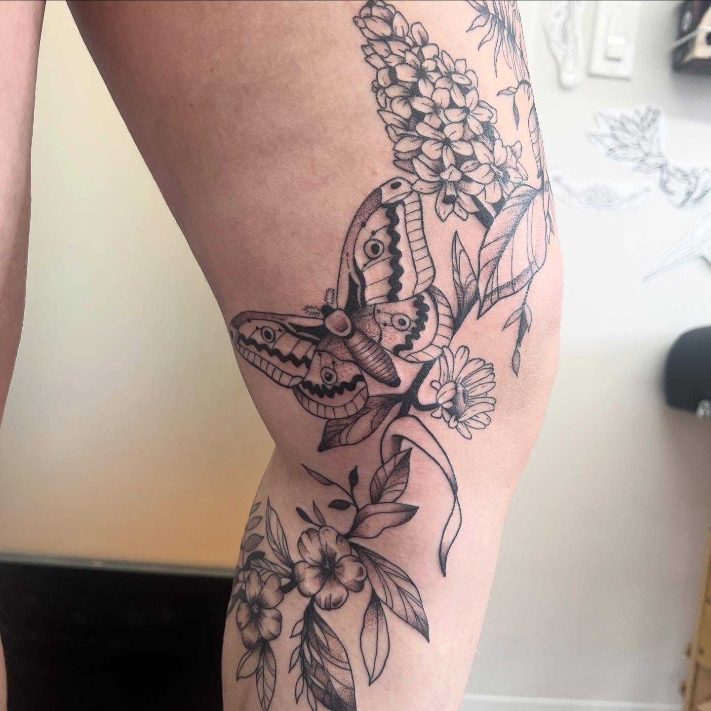 Butterfly and flowers black and grey tattoo on the thigh by 🍄‍🟫🍄Moth🍄🍄‍🟫