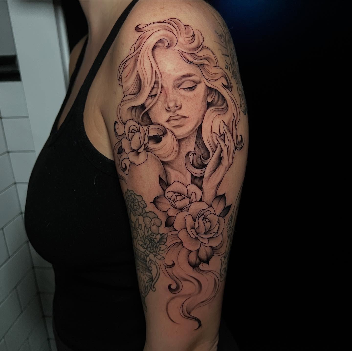 Woman with roses realism tattoo on the upper arm by l y n d s e y r i c k e t t s