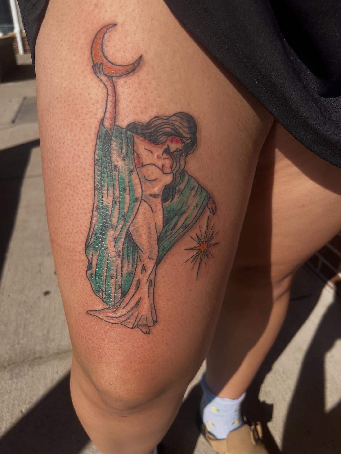 Woman holding crescent moon American traditional tattoo on the thigh by Monii Arreola