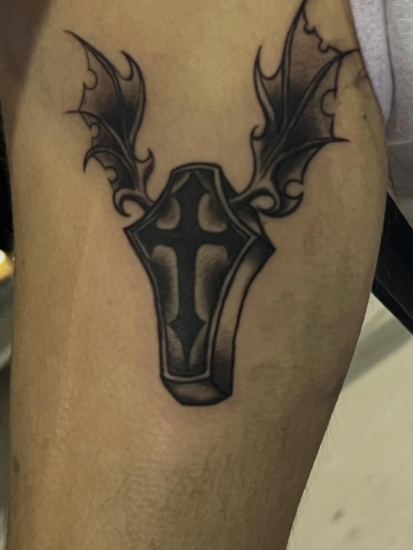 Cross with wings black and grey tattoo on the forearm by zion