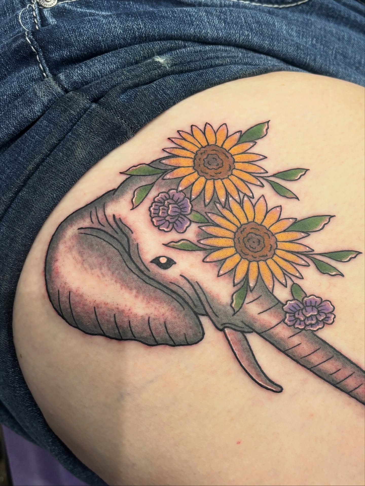 Elephant with sunflowers American traditional tattoo on the thigh by Malia Clark