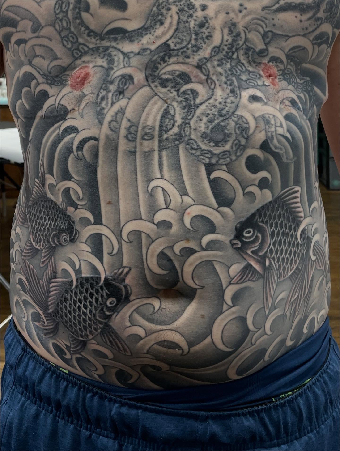 Waves and fish japanese irezumi tattoo on the torso by Haley McMahon
