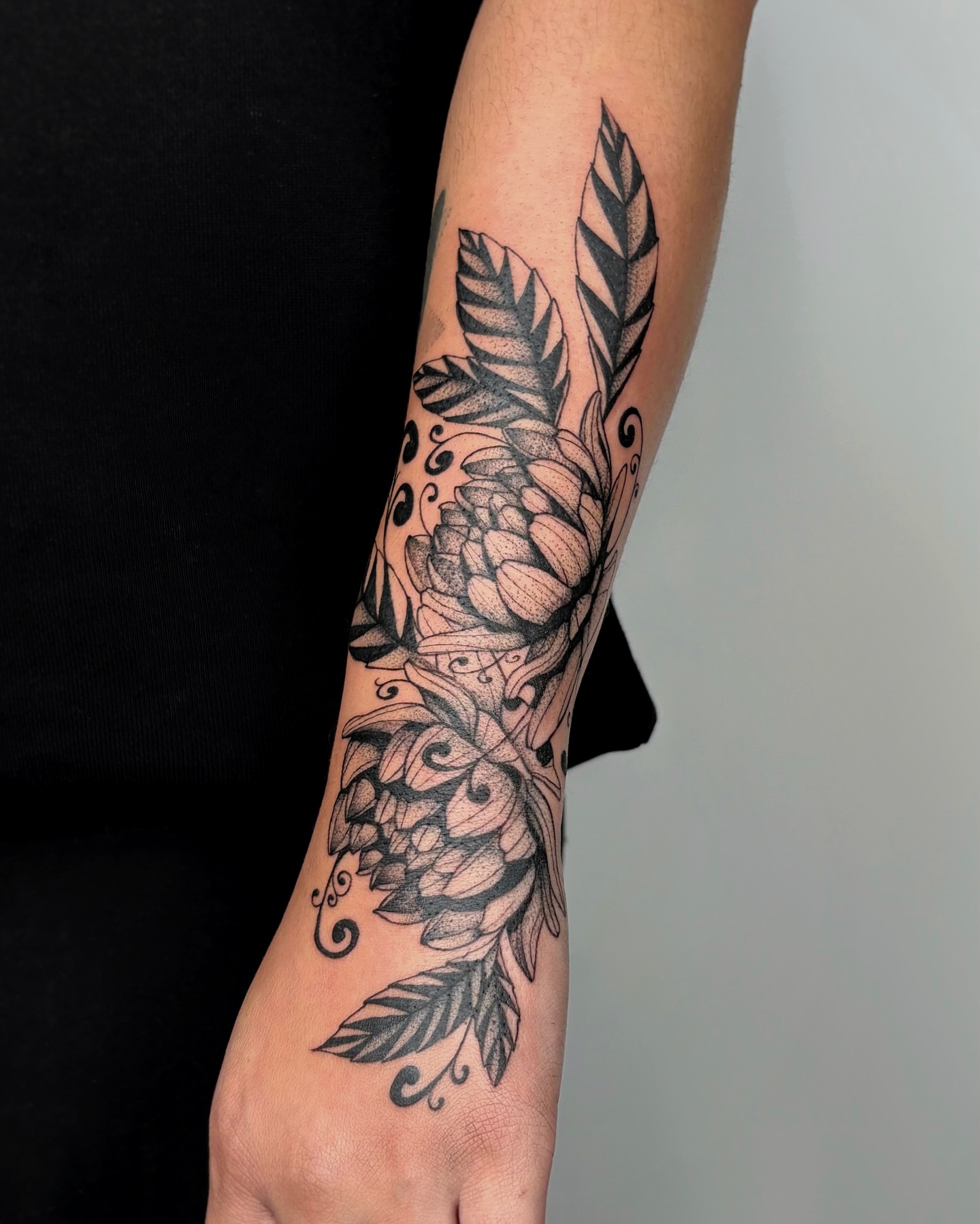 Floral arrangement black and grey tattoo on the forearm by Kuya, Berkeley, California