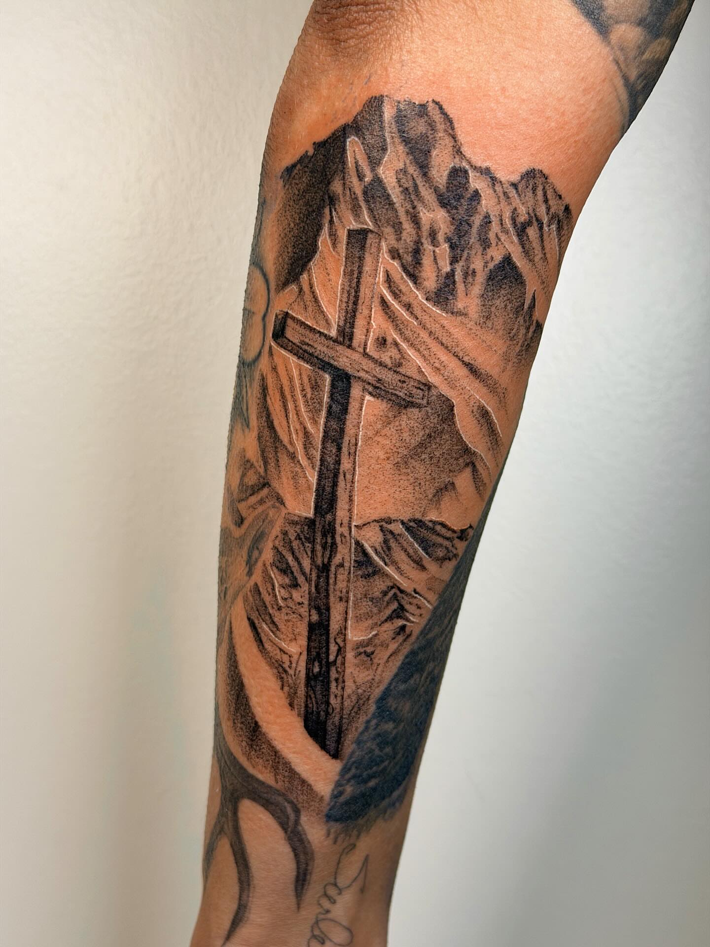 Cross and mountain realism tattoo on the forearm by Nate Weaver