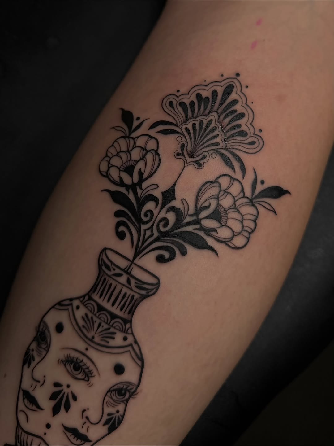 Vase with flowers and faces surrealism tattoo on the forearm by Dee, San Diego, California