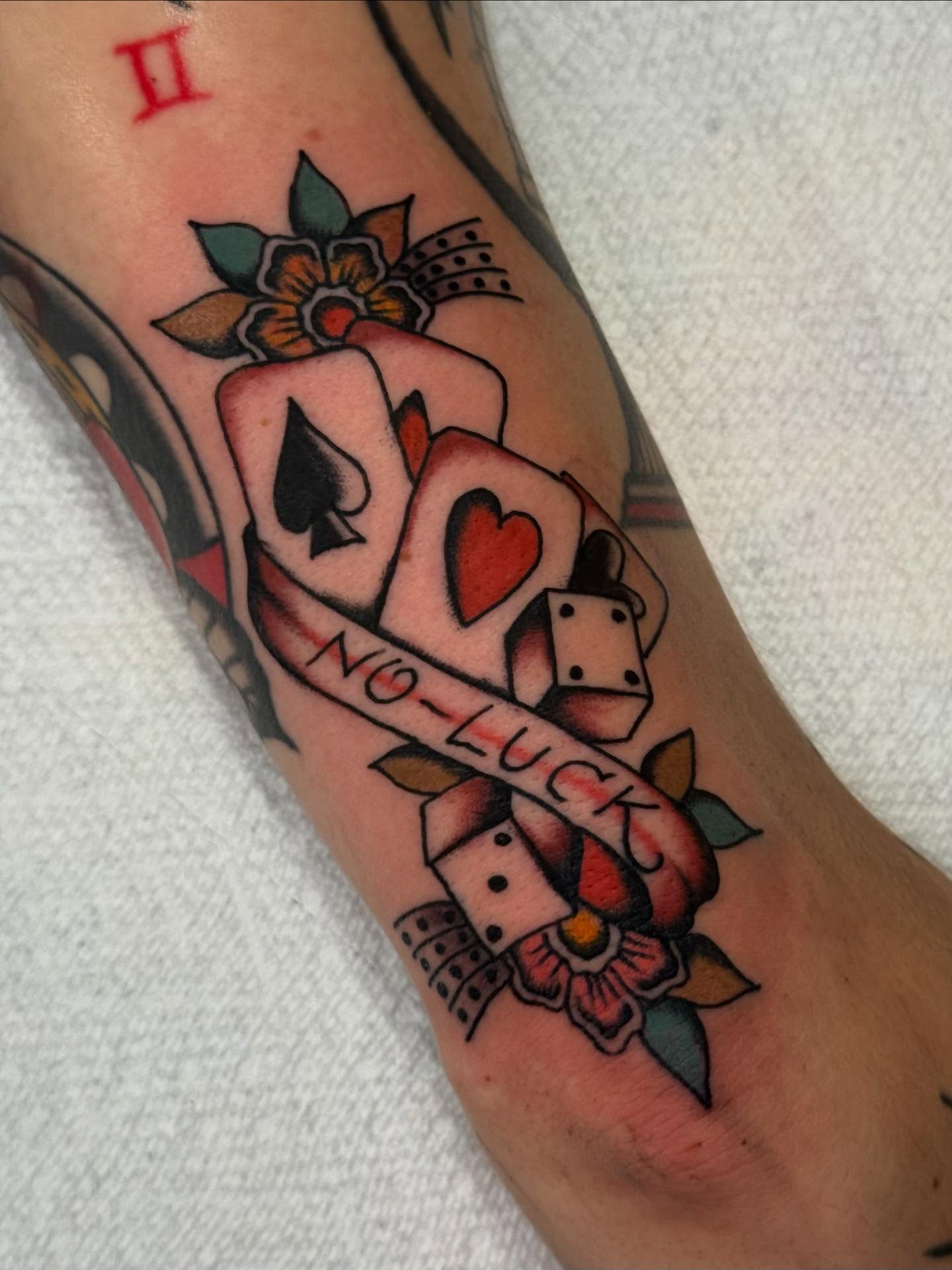 Dice and playing cards American traditional tattoo on the forearm by Cody Petkus