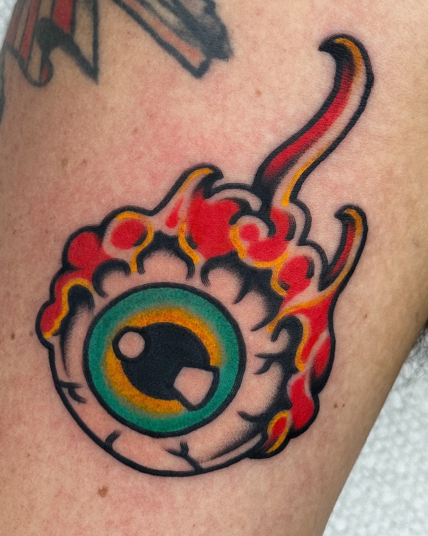 Eye with flames American traditional tattoo on the thigh by Samuel Dickey