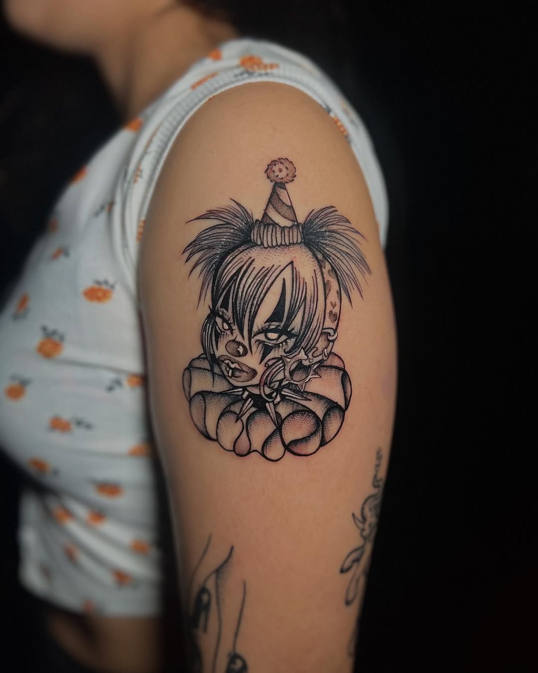 Creepy clown head realism tattoo on the upper arm by Sasha “Sashimi” Shabasov