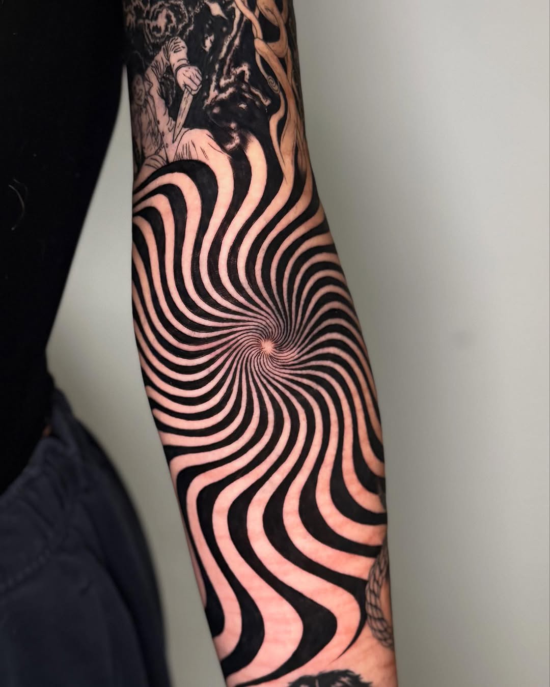 Hypnotic spiral with figures surrealism tattoo on the forearm by Erin Blaney