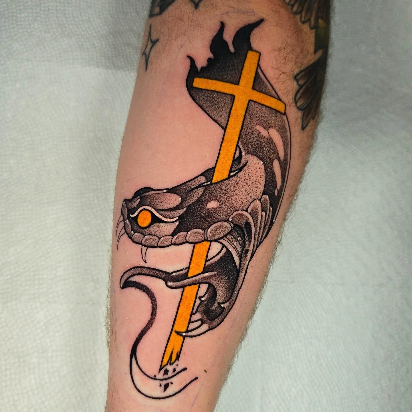 Snake and cross American traditional tattoo on the forearm by Justin Eldridge