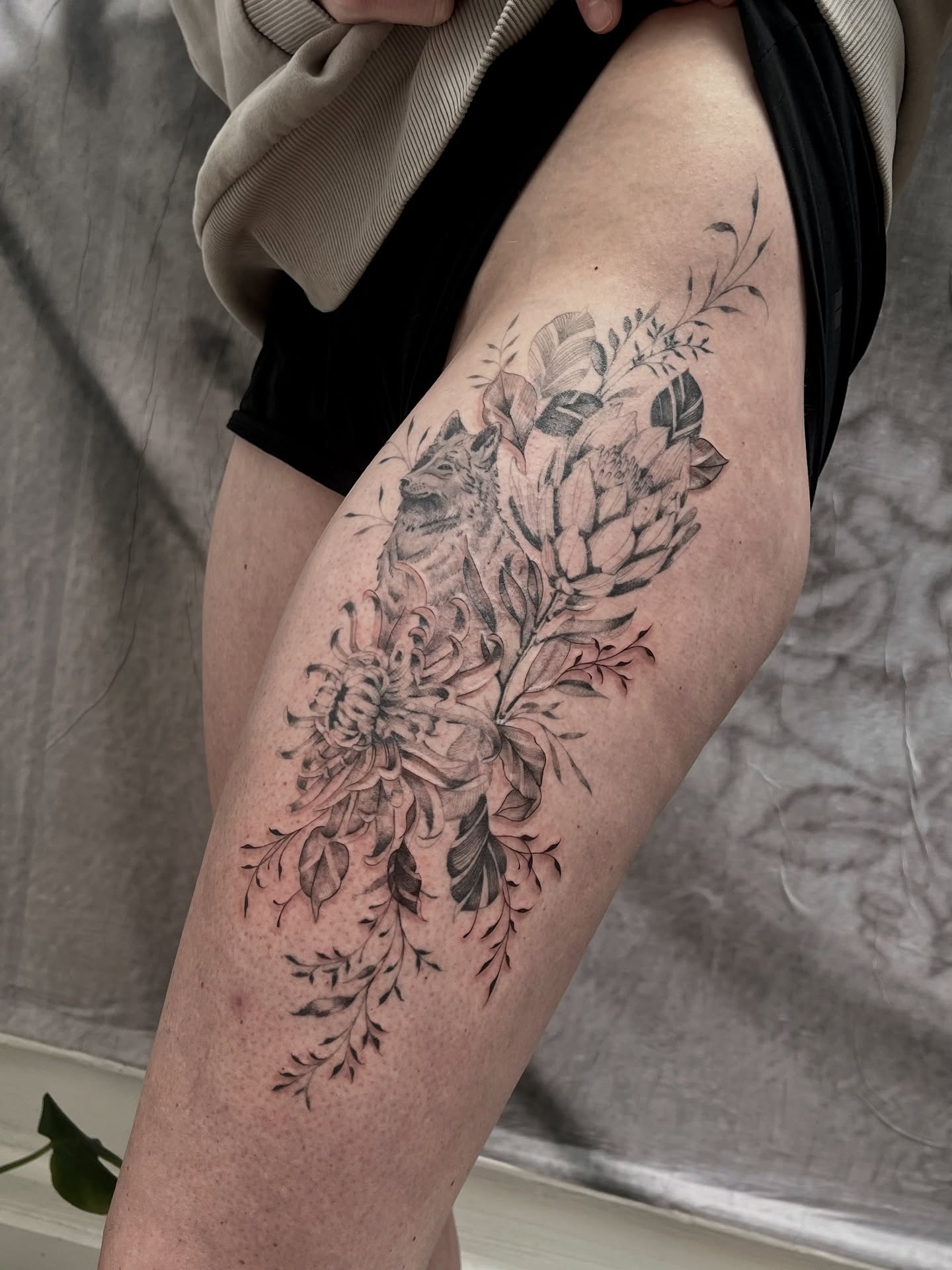 Floral arrangement black and grey tattoo on the thigh by Lo Gwynn
