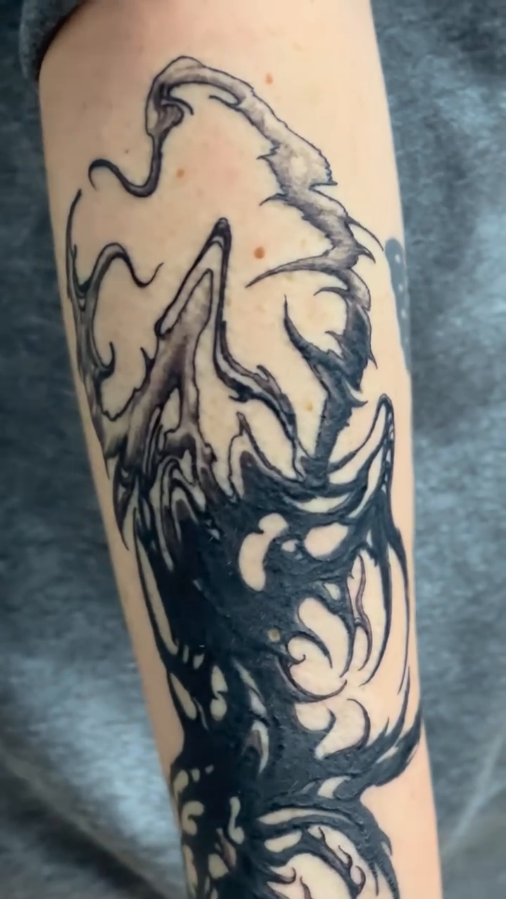 Abstract wolf head with flowing elements blackwork tattoo on the forearm by vannadoestattoos