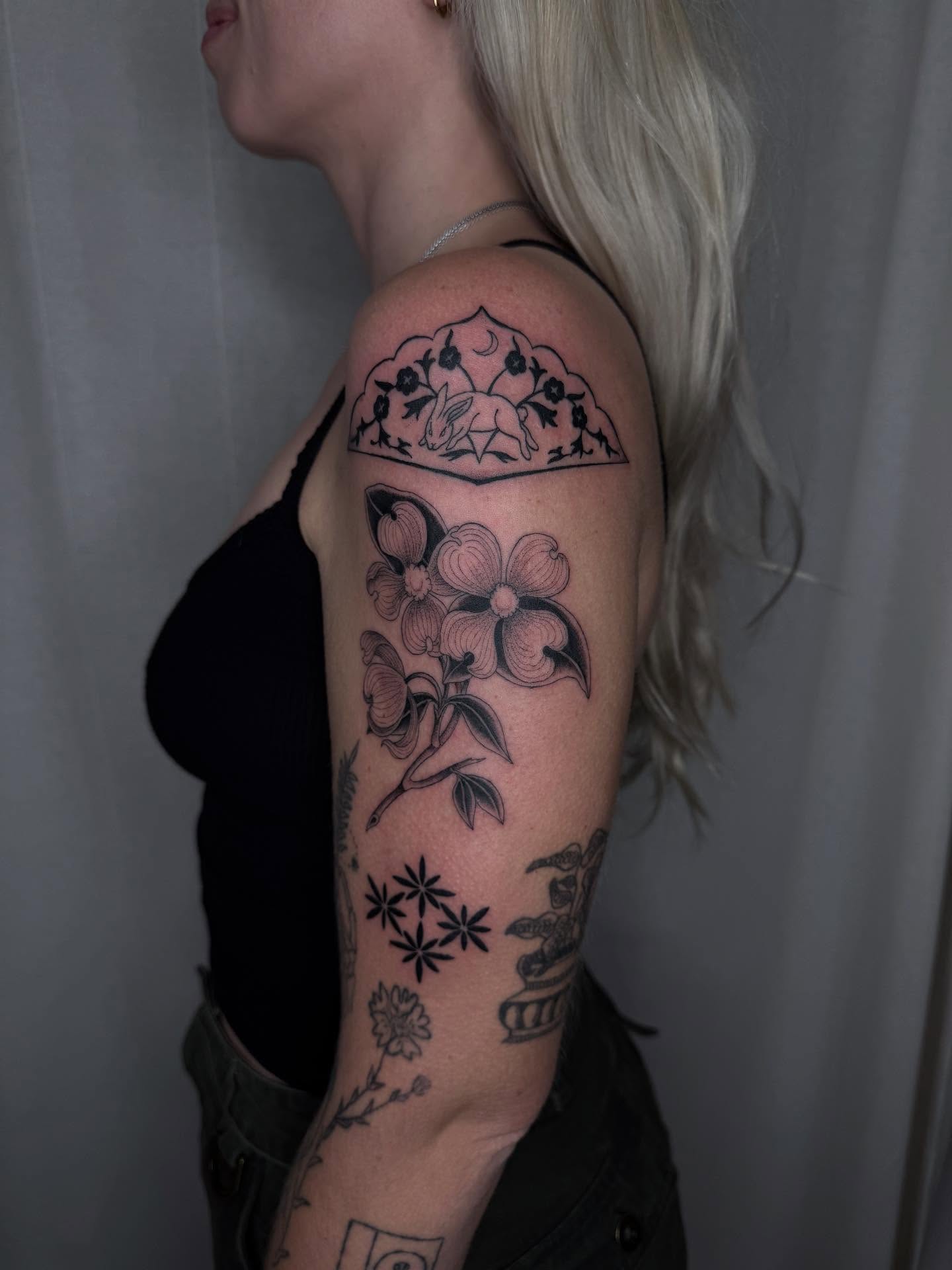 Flower and animal black and grey tattoo on the upper arm by Finley Jordan
