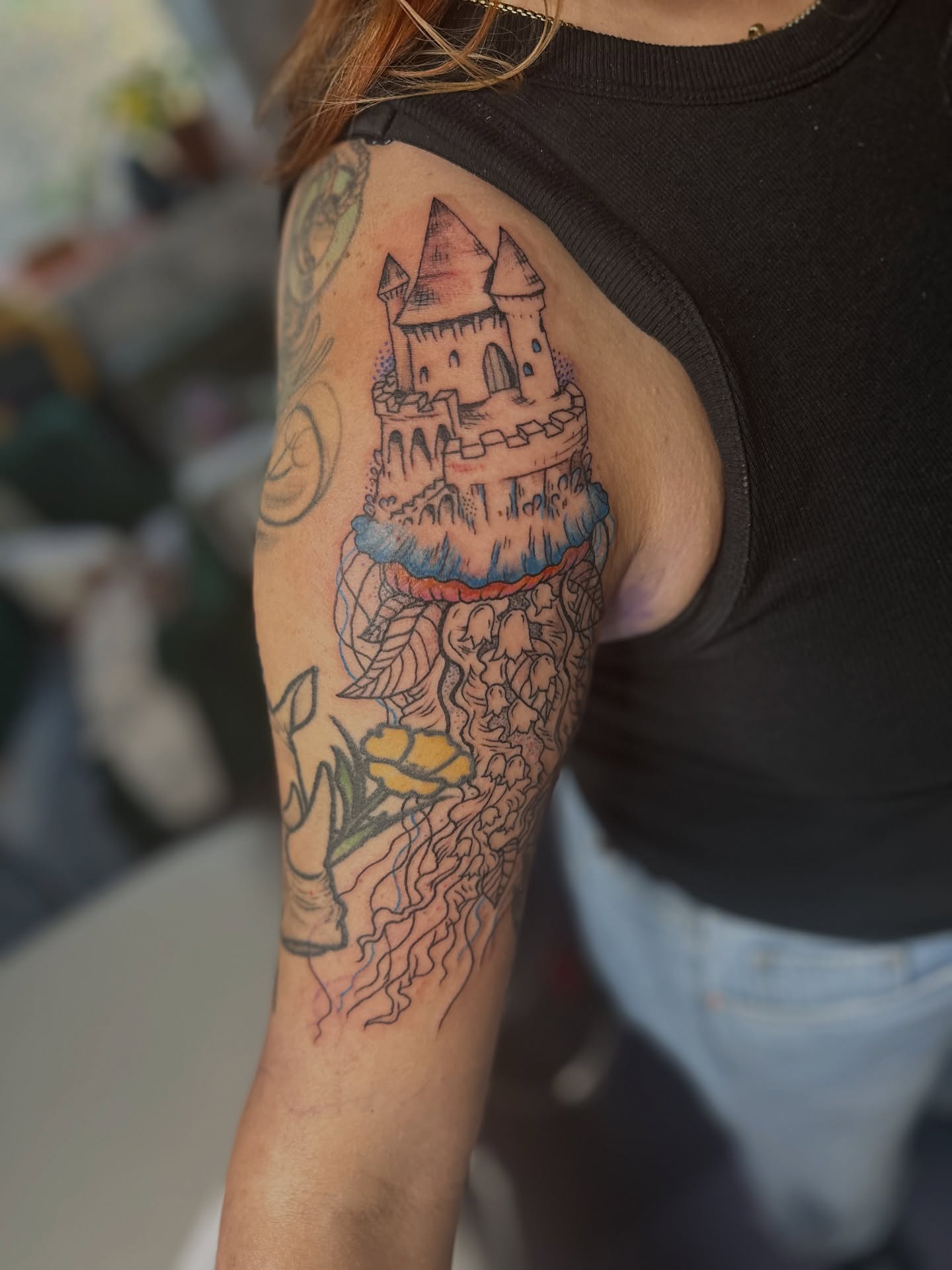 Castle on cliff neo-traditional tattoo on the upper arm by Emma Berger